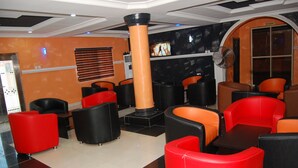 A lobby with red and black seating, a pillar, and a television screen.
