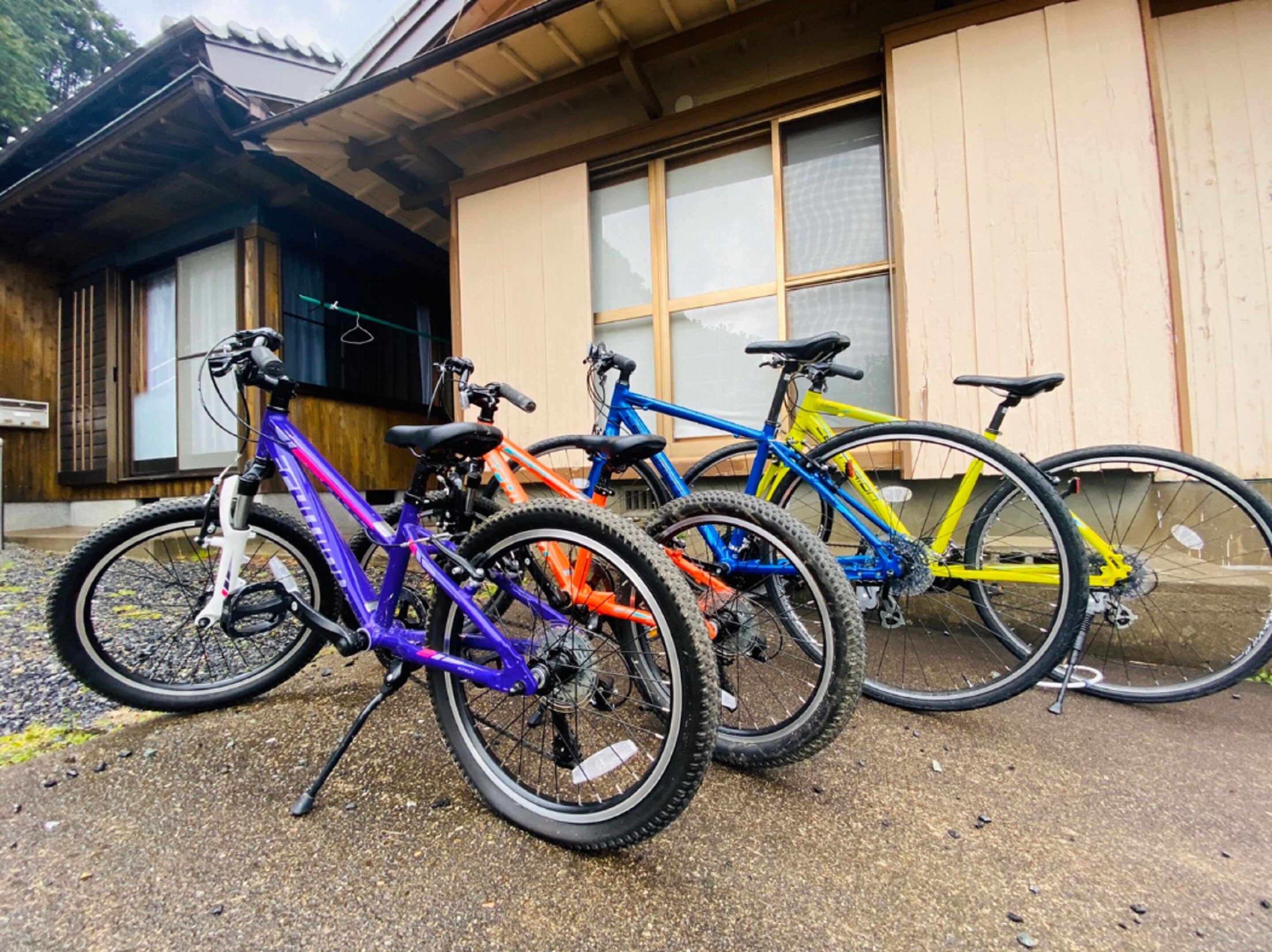Três bicicletas estacionadas em frente a um edifício com fachada de madeira e grandes janelas.