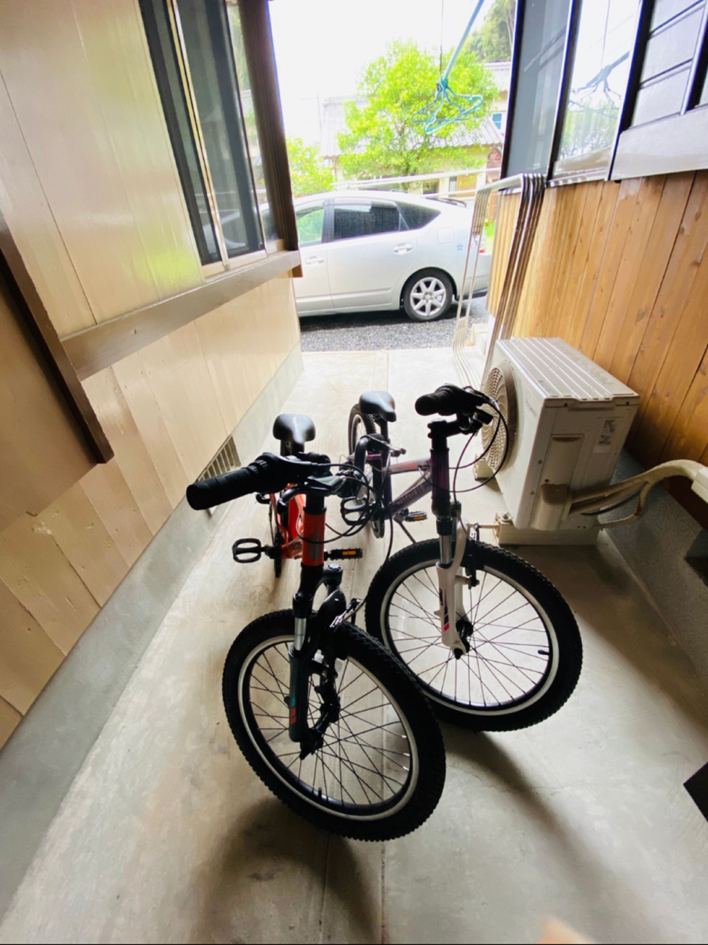 Una bicicleta estacionada dentro de un edificio, con vista a un coche a través de una ventana.