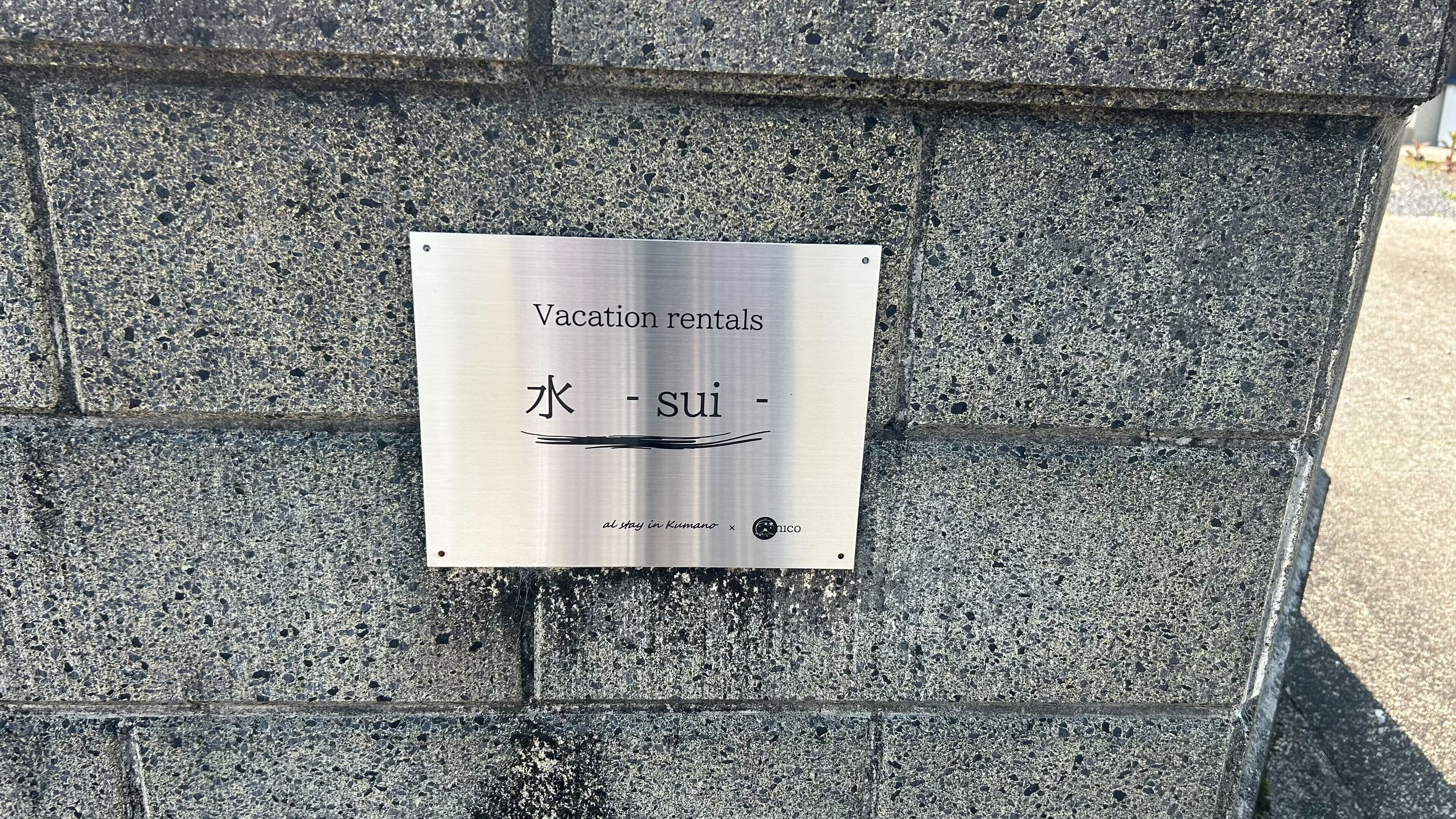 Señal de alquileres vacacionales con caracteres japoneses y un logotipo.