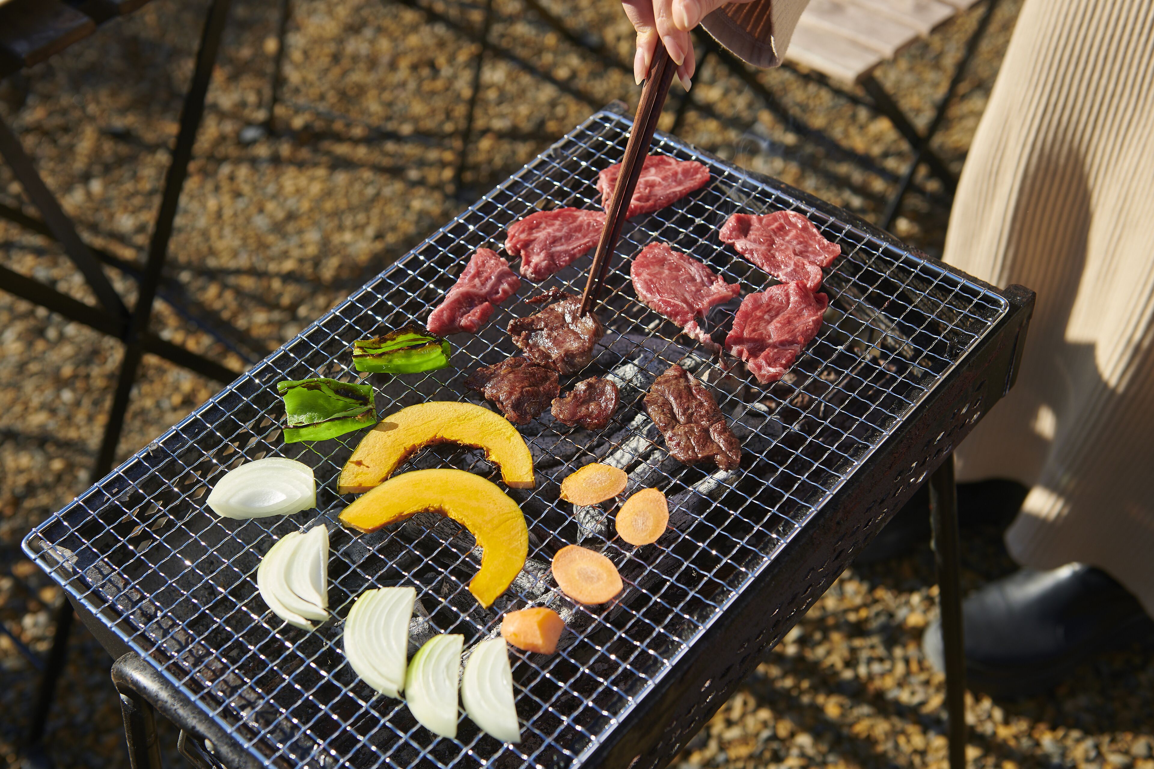 En grill med forskellige kød- og grøntsagsretter, der bliver tilberedt.