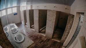 Un baño público con varios lavamanos, suelo de baldosas y techo curvo.