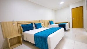 Una habitación de hotel con dos camas, cabecero de madera, mesita de noche y una puerta.