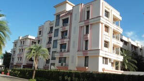 A multi-story residential building with balconies, air conditioning units, and a well-maintained hedge in front. - LBD Resorts & Hotels (Kolkata)