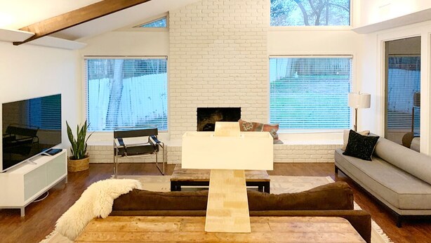 Una sala de estar moderna con chimenea de ladrillo blanco, un televisor de pantalla plana, un sofá y una mesa de centro.