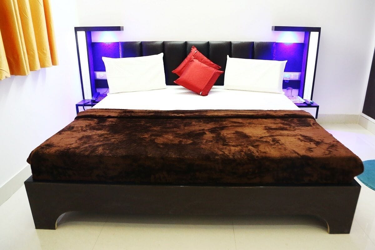 A bed with a dark headboard, white pillows, and a brown bedspread.