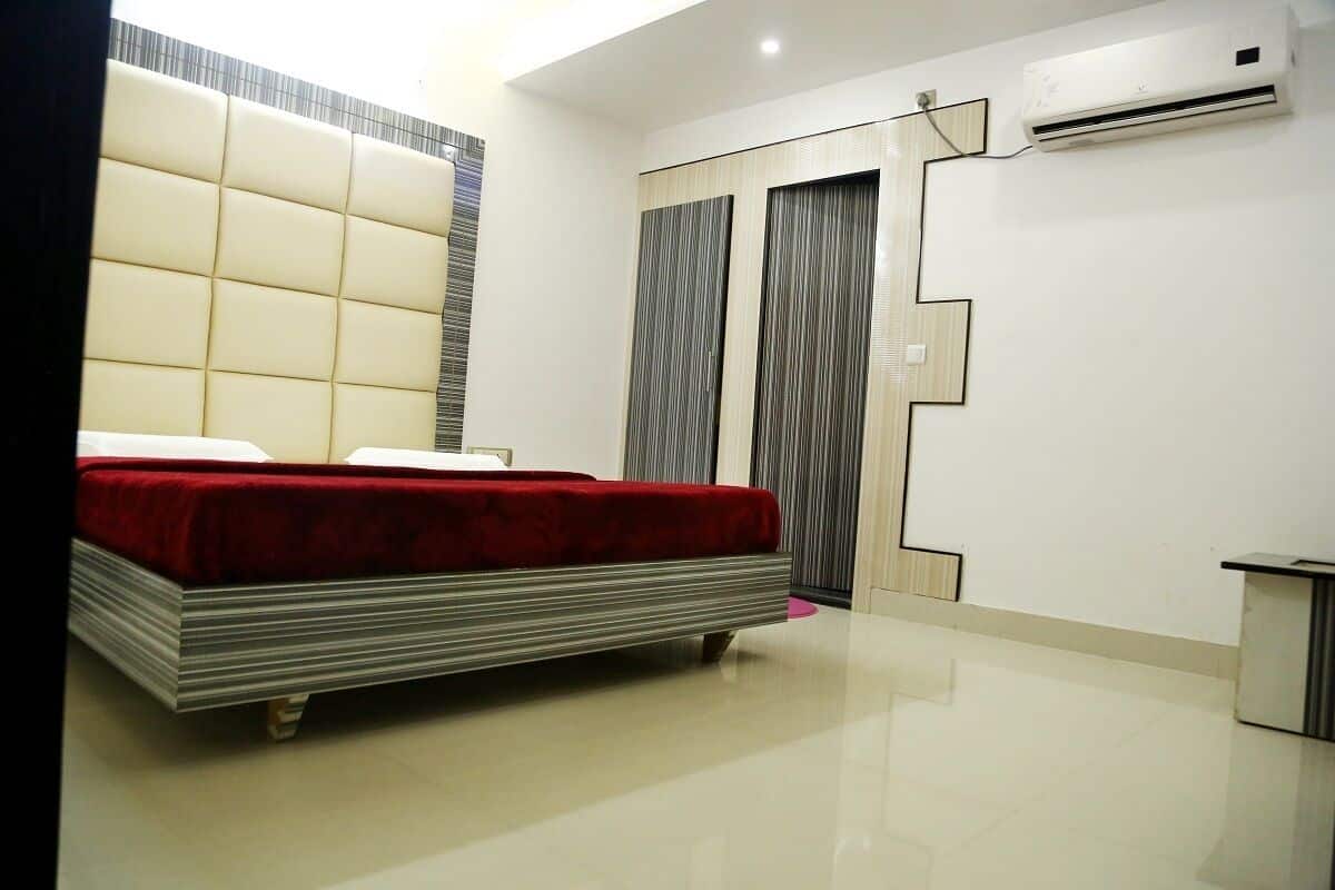 A modern bedroom with a large bed, a wardrobe, and an air conditioning unit.
