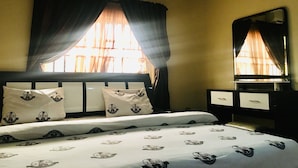 A hotel room with a bed, a nightstand, a mirror, and an air conditioning unit. - IBD International Hotel Ilaro (Ilaro)