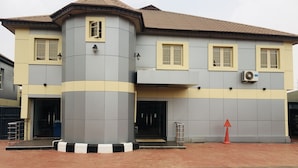 A two-story building with a grey and yellow facade, a tiled roof, and a small balcony. - IBD International Hotel Ilaro (Ilaro)