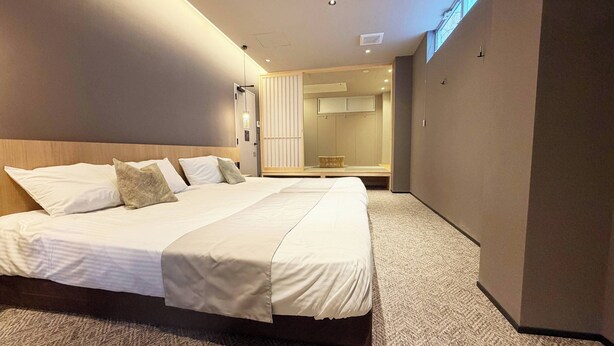 Une chambre d’hôtel moderne avec un grand lit, un dressing et un grand miroir.