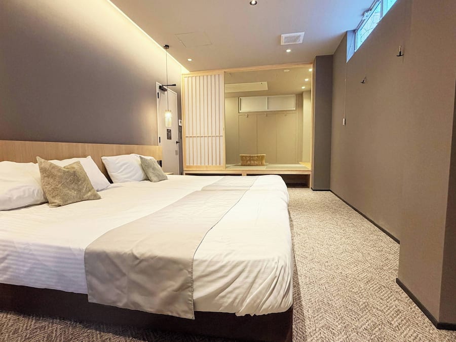 A modern hotel room with a large bed, a walk-in closet, and a large mirror.