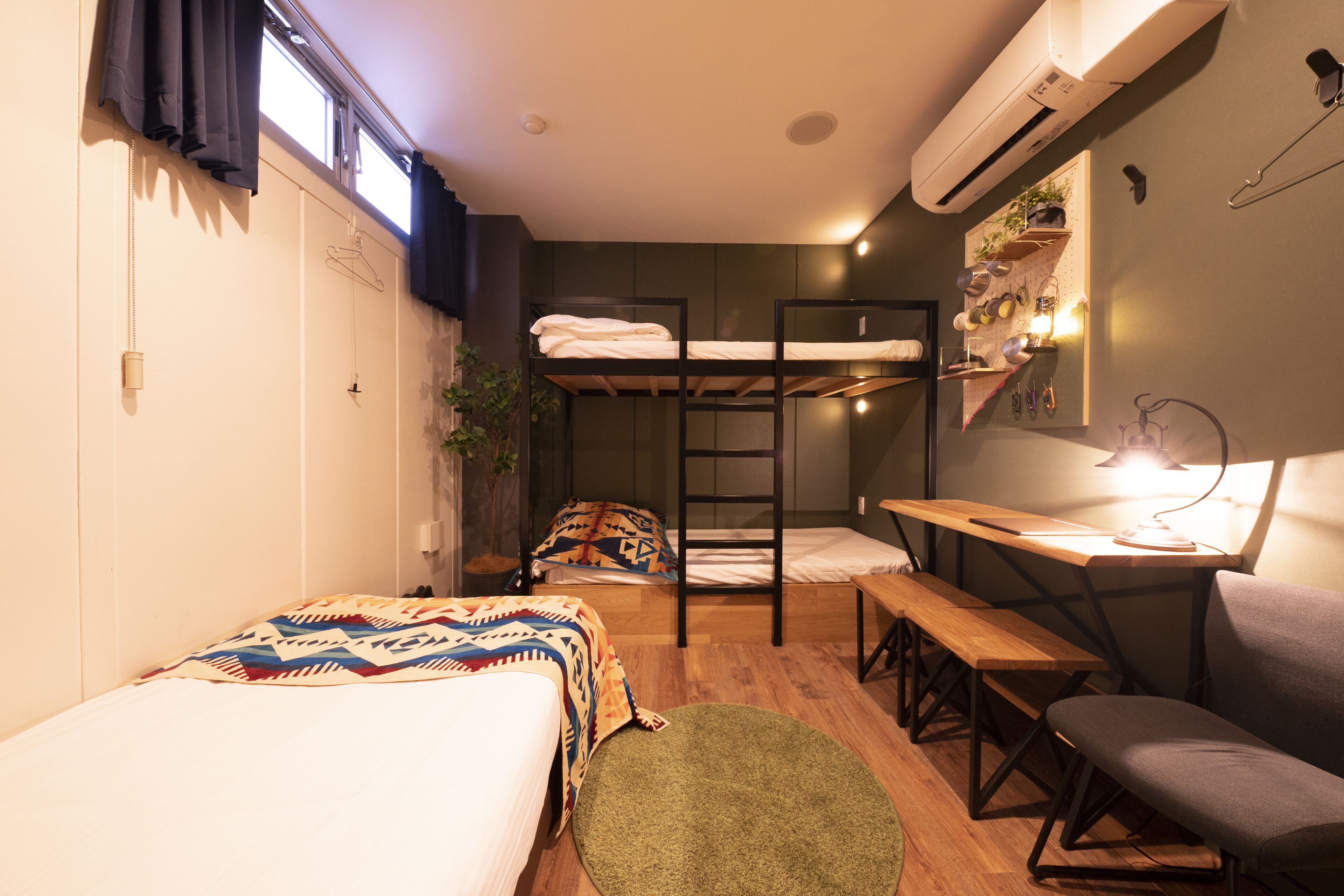 A compact room with bunk beds, a desk, and a bench.