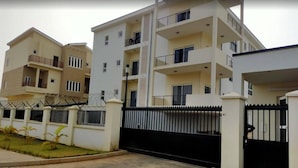 A multi-story residential building with balconies, a gated entrance, and a paved driveway. - The Capital (Abuja)