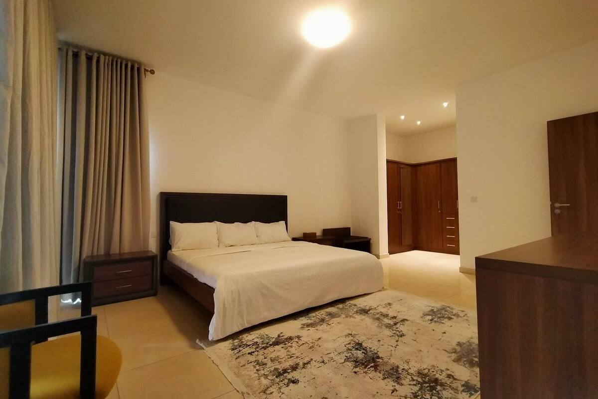 A bedroom with a bed, nightstands, a wooden wardrobe, and a chair.