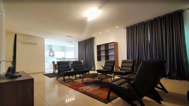 A modern living room with a flat-screen TV, a coffee table, and a sofa set. - The Capital (Abuja)