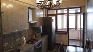 Eine moderne Küche mit Einbauofen, Mikrowelle und Kühlschrank. Ein Esstisch mit Stühlen und eine Chandelier leuchten darüber.
