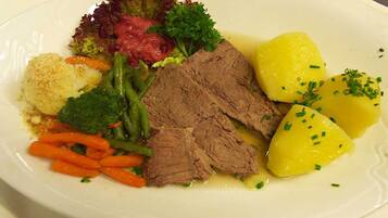 A plate of food with beef, potatoes, carrots, and greens.