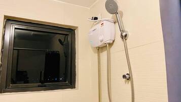 Une salle de bain avec une fenêtre, une pomme de douche et un pommeau de douche amovible.