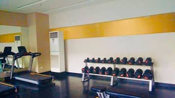 A gym with treadmills, dumbbells, and a bench.