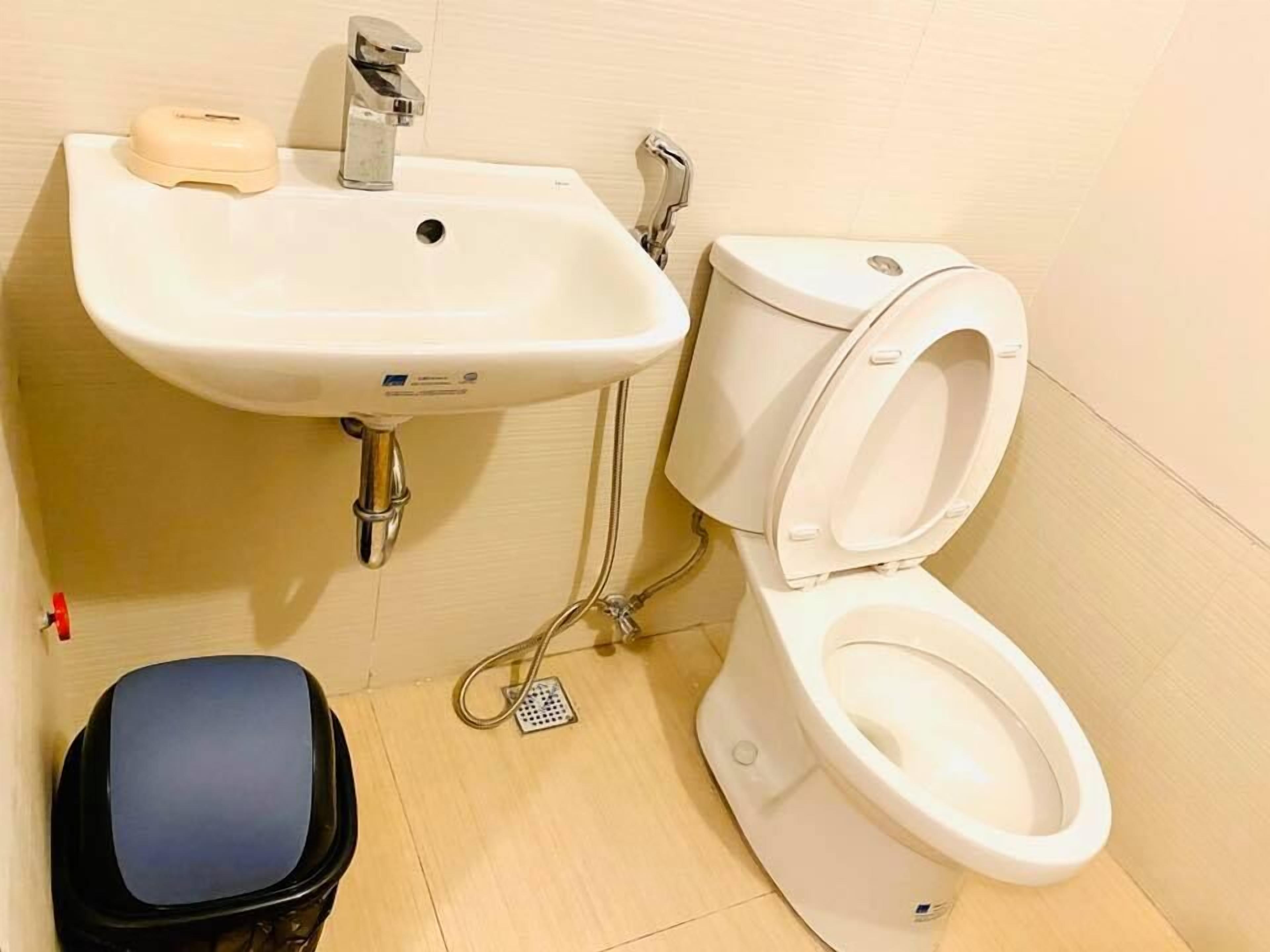 Une salle de bain avec un lavabo blanc, des toilettes et une poubelle.