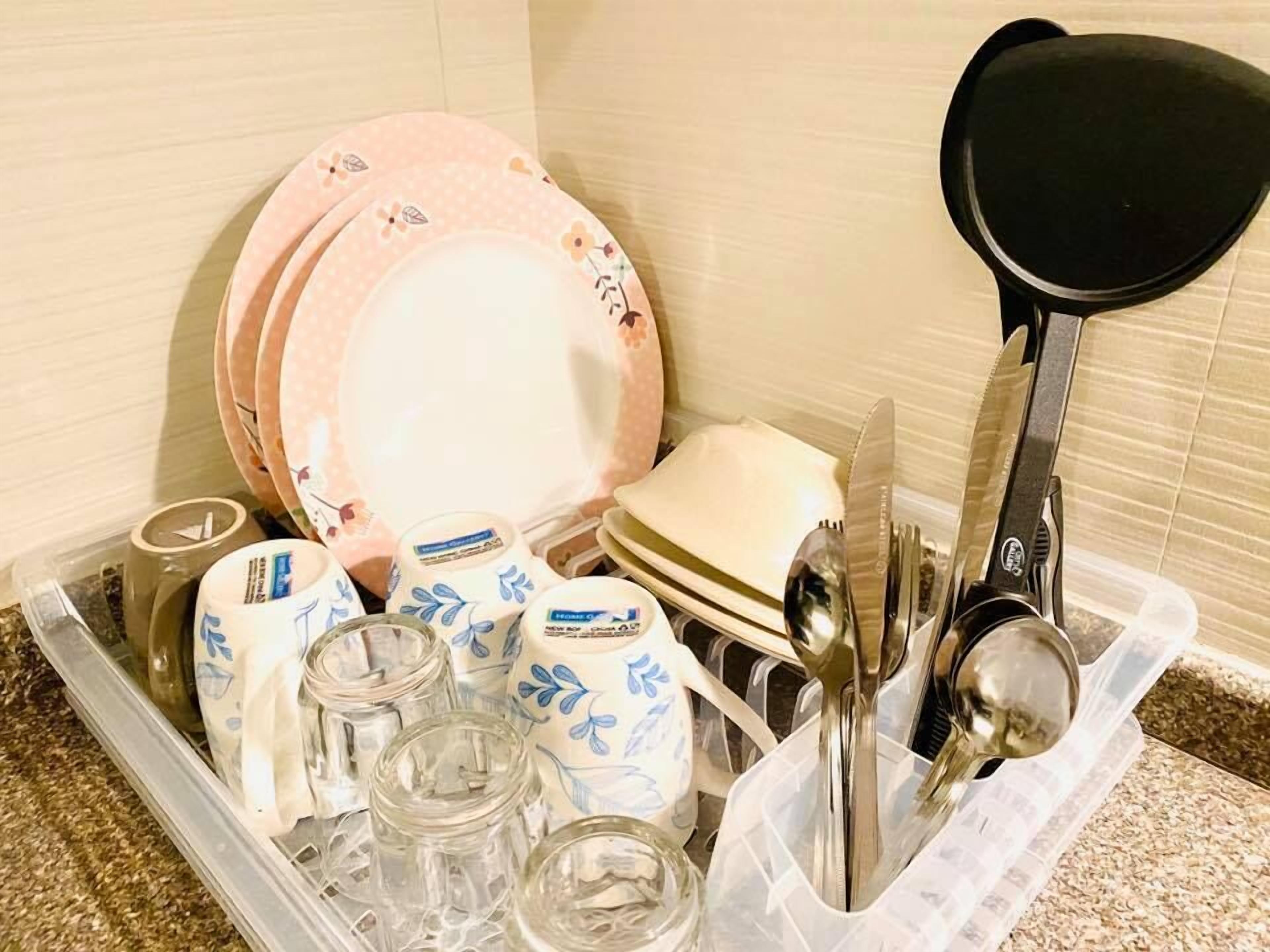 A kitchen drawer containing various dishes, utensils, and glassware.