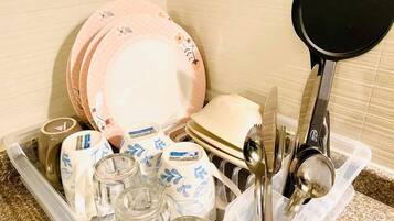 A kitchen drawer containing various dishes, utensils, and glassware.
