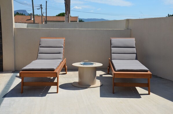 Una terraza en la azotea con dos sillones y una mesita.