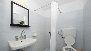 A modern bathroom with a sink, mirror, toilet, and shower curtain. - Twin Shades (Kalymnos)
