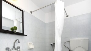 A bathroom with a sink, toilet, and shower curtain. - Twin Shades (Kalymnos)