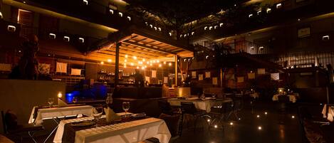An outdoor dining area with tables and chairs, a bar, and a staircase leading to an upper level.
