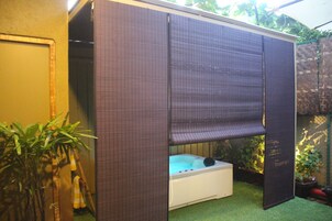 A spa area with a hot tub, bamboo plants, and a privacy screen.