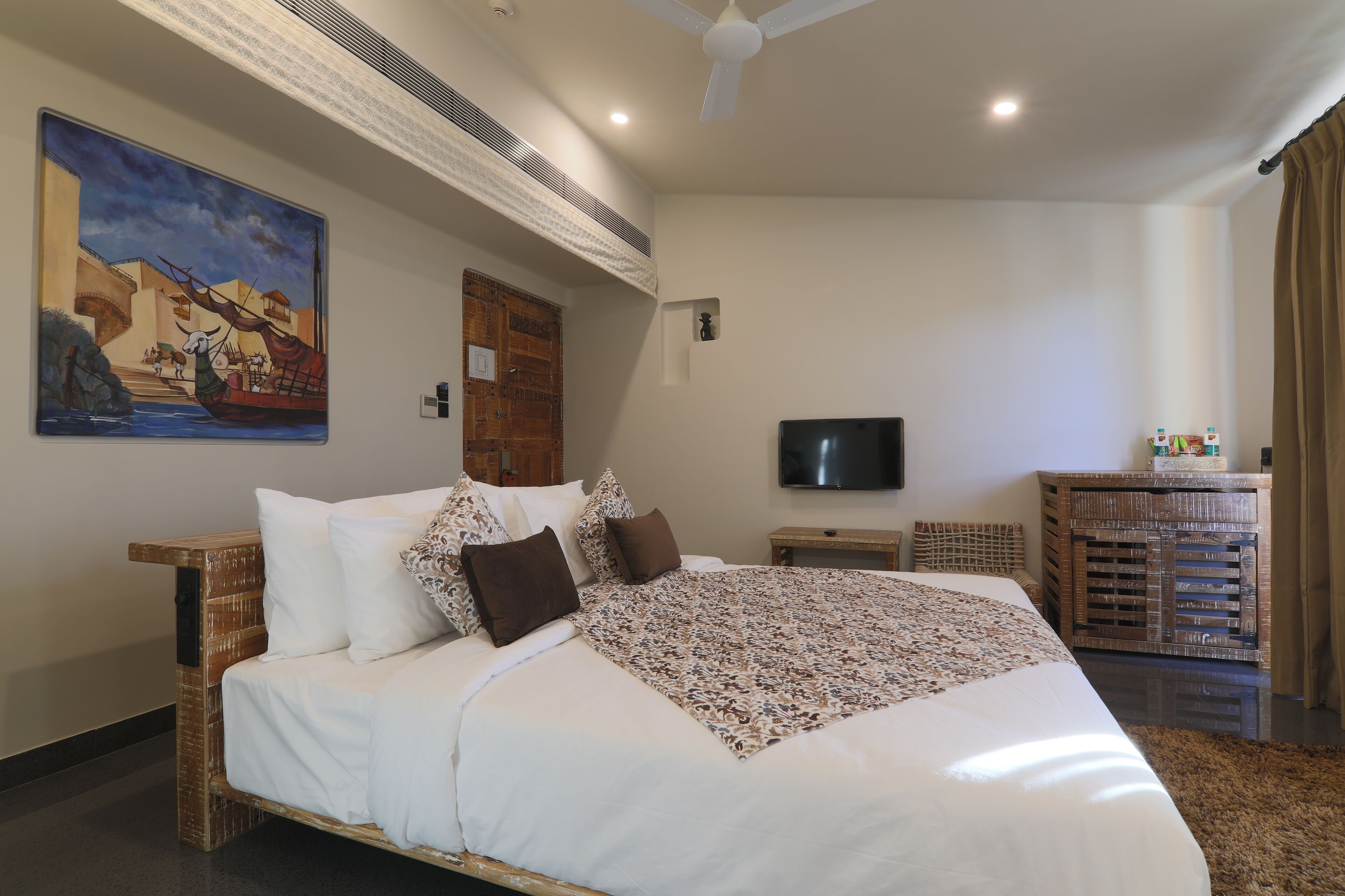 Une chambre à coucher avec un grand lit, une télévision, une armoire en bois et un tableau au mur.