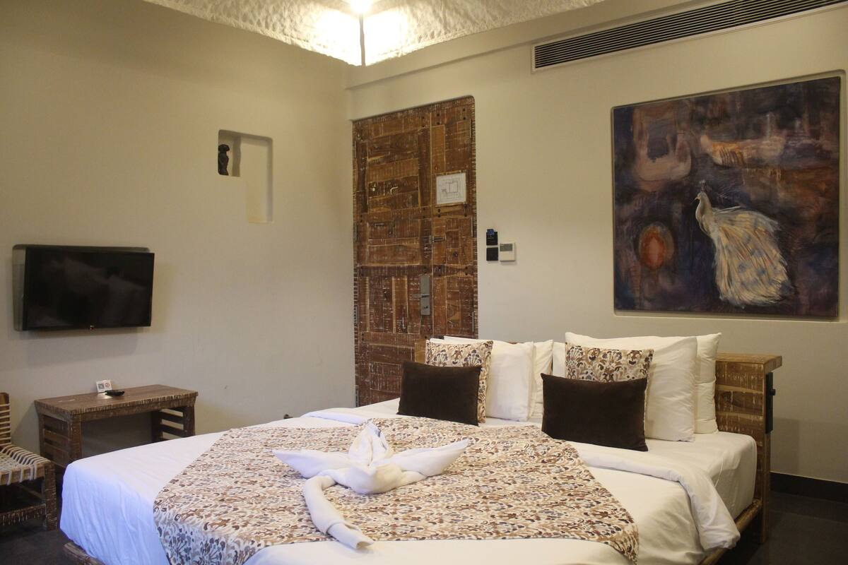 Habitación de hotel con una cama grande, televisión de pantalla plana, escritorio de madera y un cuadro en la pared.