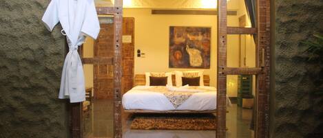 A bedroom with a bed, a painting on the wall, and a robe hanging on a hook.