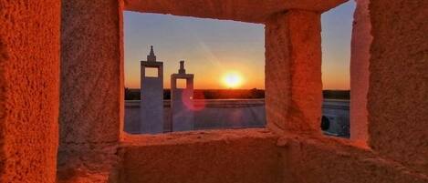 A stone structure with a window framing a sunset view.