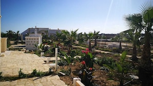 Zona residencial con un sendero pavimentado que lleva a un edificio de fachada blanca y balcón.