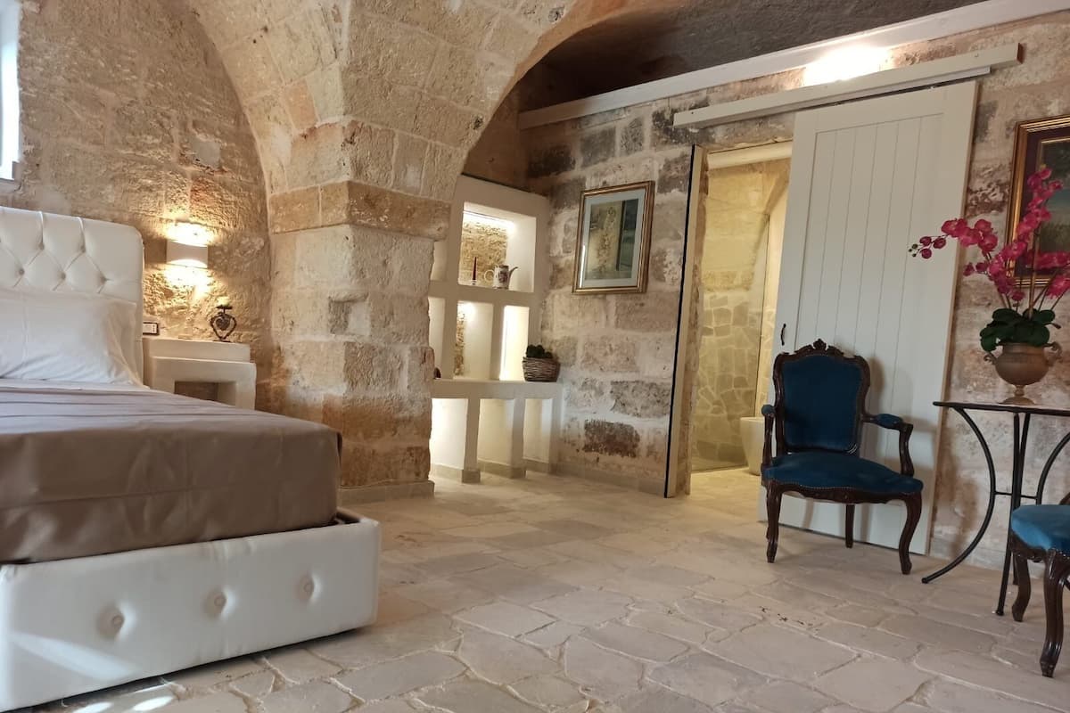 A stone-walled bedroom with a bed, a chair, and a small table.