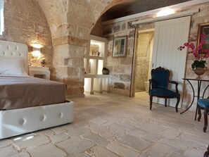 A stone-walled bedroom with a bed, a chair, and a small table. - Agriturismo Mascava di Torre Guaceto (Brindisi)
