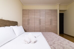 A hotel room with a bed, white linens, a brown headboard, and a wardrobe with wooden doors. - Thresh Apartments Airport by Airstay (Spata-Artemida)