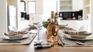 A dining table set with plates, cutlery, a wine bottle, and a glass. - Thresh Apartments Airport by Airstay (Spata-Artemida)