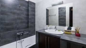 A modern bathroom with a bathtub, a sink, and a mirror.