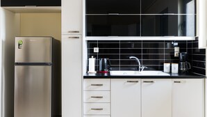 A modern kitchen with a stainless steel refrigerator, black tiled backsplash, white cabinets, and a black countertop. - Thresh Apartments Airport by Airstay (Spata-Artemida)