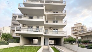 A multi-story residential building with balconies, a central entrance, and a paved pathway leading to the entrance. - Thresh Apartments Airport by Airstay (Spata-Artemida)