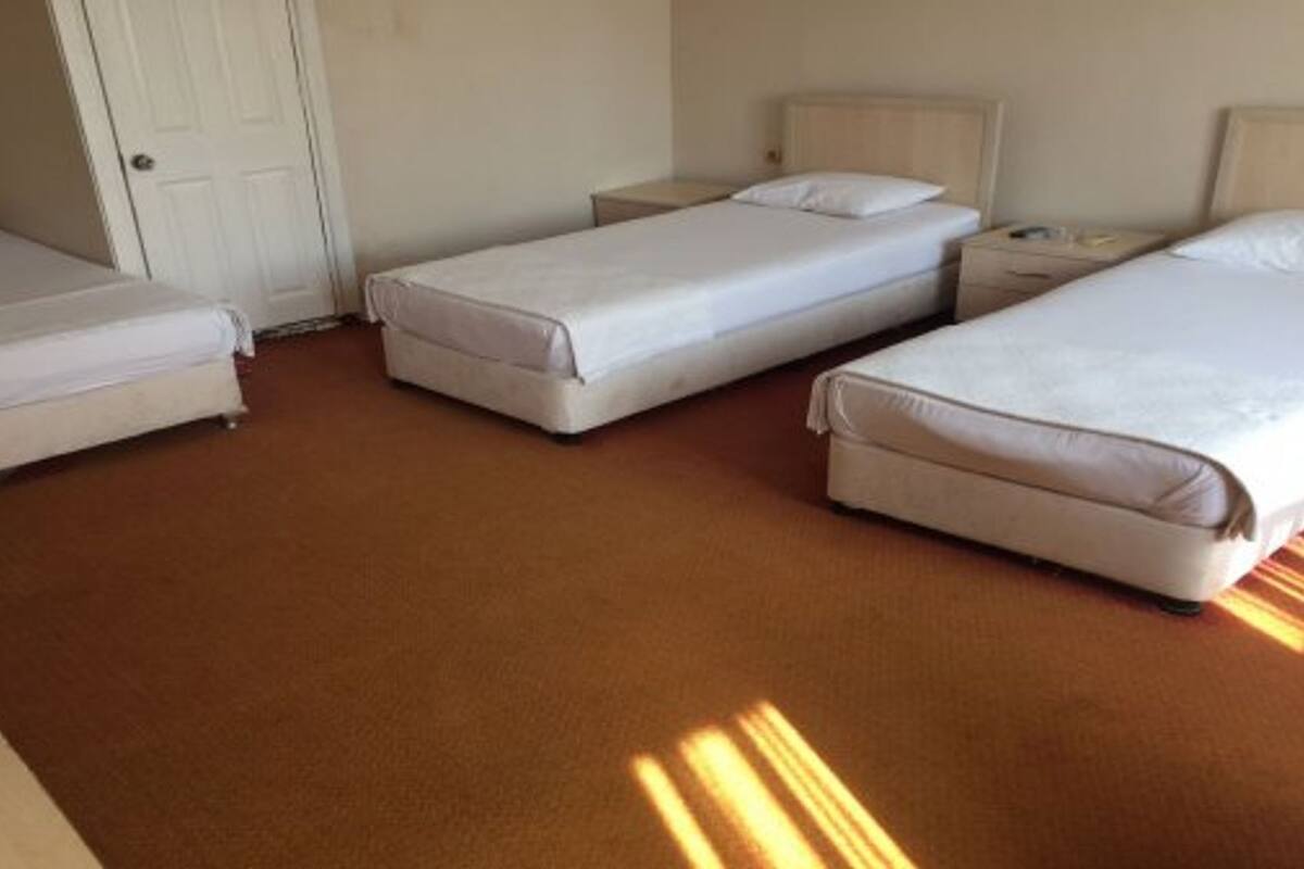 Habitación de hotel con tres camas individuales, un escritorio y una silla.