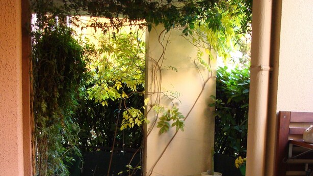 An outdoor patio with a table and chairs, surrounded by greenery and a wall. - T4 near Hypercentre, private car box and loggia (Toulouse)