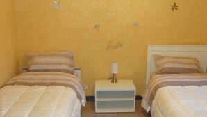 A room with two beds, a nightstand with a lamp, and a wall with a 'hello' sign. - T4 near Hypercentre, private car box and loggia (Toulouse)