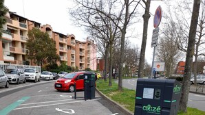 A parking area with marked spaces, a red car, and a black electric vehicle charging station. - T4 near Hypercentre, private car box and loggia (Toulouse)