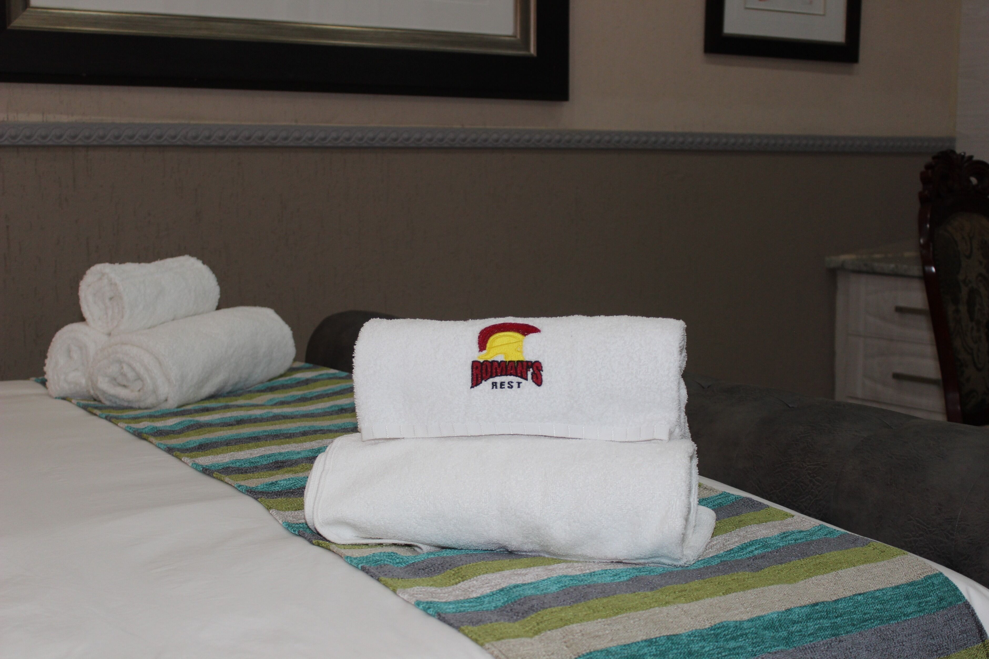 Una habitación de hotel con una cama bien hecha, un tapete a rayas y un cuadro en la pared.