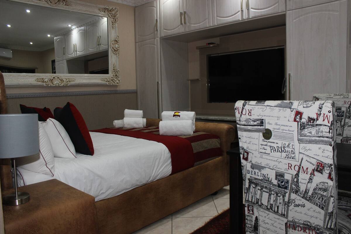 Une chambre d’hôtel avec un grand lit, une télévision et un mur décoré d’images représentant des paysages urbains.