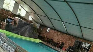 Ein Poolbereich im Innenbereich mit Holzterrasse und überdachter Sitzecke.